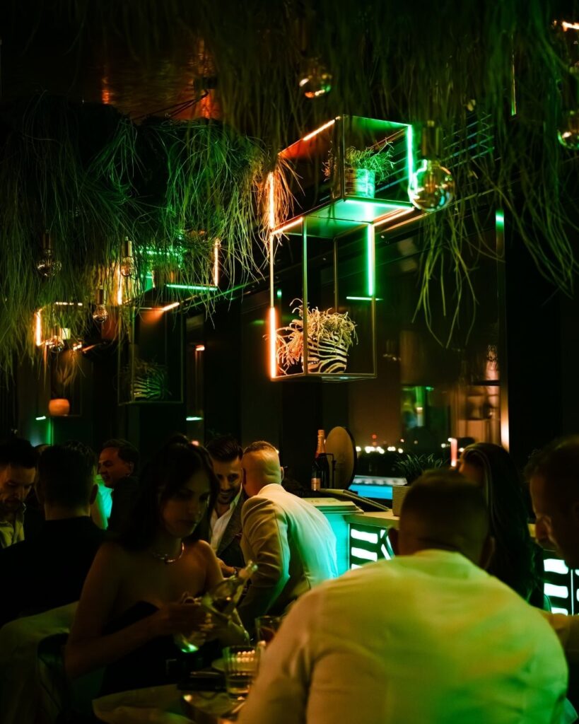 Éjszakai bár hangulat a Selva Skybarban vendégekkel és zöld neon fényekkel