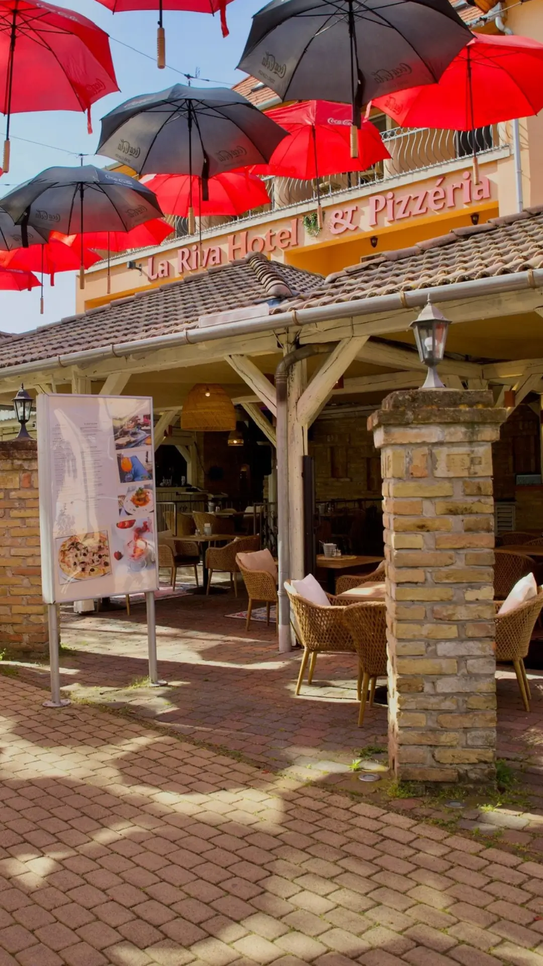 A La Riva Hotel & Pizzéria ikonikus, színes esernyőkkel díszített terasza a Petőfi sétányon – hangulatos szabadtéri helyszín.